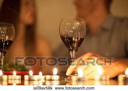 Stock Image - Couple enjoying a glass of red wine by candlelight. Fotosearch