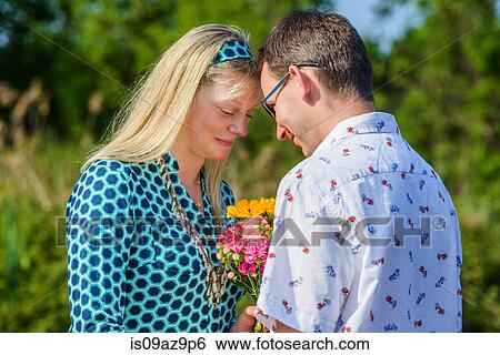 Couple face to face holding flowers View Large Photo Image Stock Photograph - Couple face to face holding flowers. Fotosearch