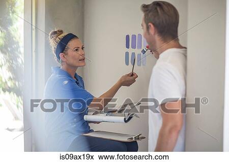 Couple holding brochure discussing paint colours on wall View Large Photo Image Stock Photo - Couple holding brochure discussing paint colours on wall. Fotosearch
