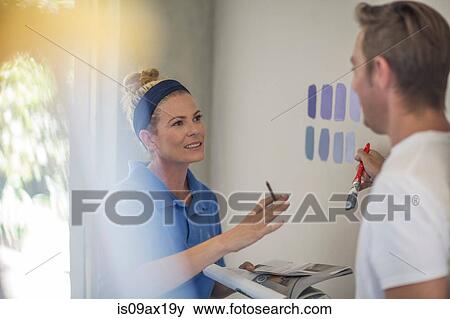 Couple holding brochure discussing paint colours on wall View Large Photo Image Stock Photo - Couple holding brochure discussing paint colours on wall. Fotosearch