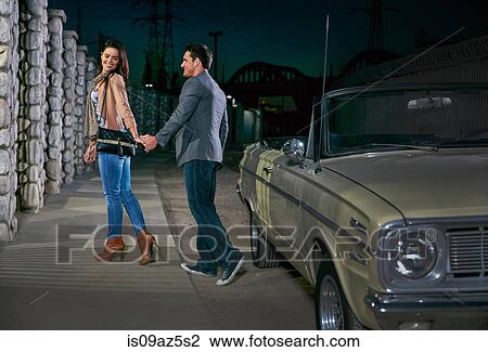 Couple holding hands in street by convertible classic car at night, Los Angeles, California, USA View Large Photo Image Stock Image - Couple holding hands in street by convertible classic car at night, Los Angeles, California, USA. Fotosearch