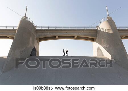 Stock Photography - Couple holding hands under bridge, Van Nuys, California, USA. Fotosearch
