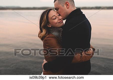 Stock Image - Couple hugging and kissing by sea, Ottawa, Ontario. Fotosearch