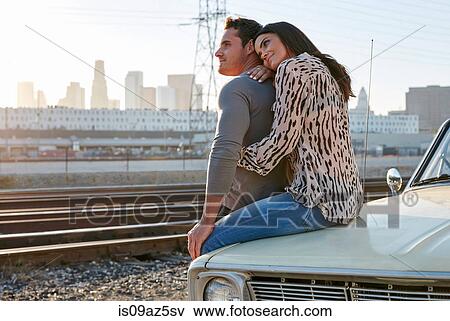 Couple hugging on car bonnet looking away, Los Angeles, California, USA View Large Photo Image Stock Photo - Couple hugging on car bonnet looking away, Los Angeles, California, USA. Fotosearch
