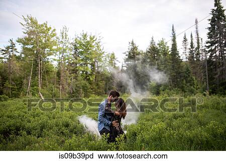 Stock Image - Couple hugging on grass field, Ottawa, Ontario. Fotosearch