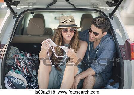 Couple in car boot looking at bikini top smiling View Large Photo Image Stock Photo - Couple in car boot looking at bikini top smiling. Fotosearch