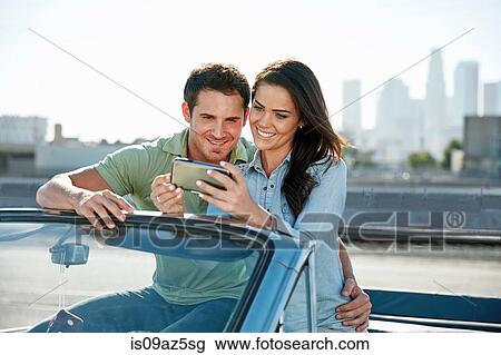 Couple in convertible car looking at smartphone, Los Angeles, California, USA View Large Photo Image Stock Image - Couple in convertible car looking at smartphone, Los Angeles, California, USA. Fotosearch