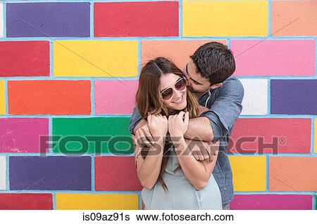 Stock Photograph - Couple in front of colourful tiled wall hugging, Coney island, Brooklyn, New York, USA. Fotosearch