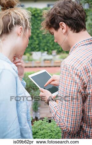 Couple in garden using digital tablet View Large Photo Image Stock Photography - Couple in garden using digital tablet. Fotosearch