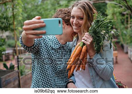 Couple in garden with carrots, taking selfie View Large Photo Image Stock Photography - Couple in garden with carrots, taking selfie. Fotosearch