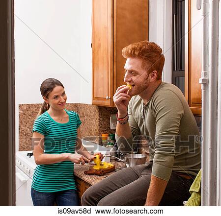 Stock Image - Couple in kitchen preparing meal smiling. Fotosearch