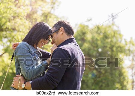 Couple in park face to face hugging and smiling View Large Photo Image Stock Image - Couple in park face to face hugging and smiling. Fotosearch