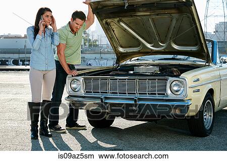 Couple looking at car engine making telephone call, Los Angeles, California, USA View Large Photo Image Picture - Couple looking at car engine making telephone call, Los Angeles, California, USA. Fotosearch