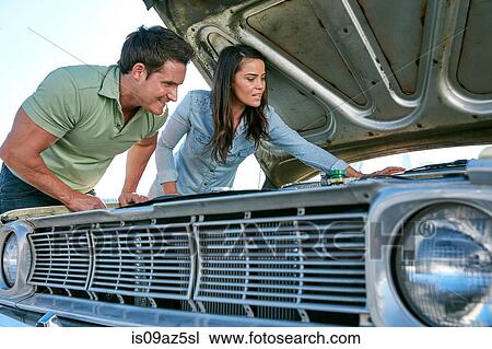 Stock Image - Couple looking at car engine smiling, Los Angeles, California, USA. Fotosearch