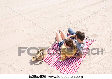 Stock Photograph - Couple lying on picnic blanket on beach, Coney island, Brooklyn, New York, USA. Fotosearch