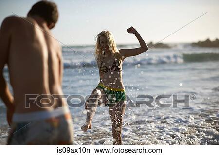 Couple on beach splashing in ocean View Large Photo Image Picture - Couple on beach splashing in ocean. Fotosearch