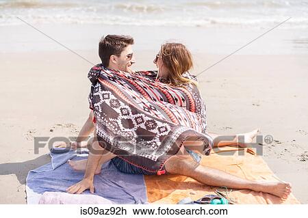 Stock Image - Couple on beach wrapped in blanket, Coney island, Brooklyn, New York, USA. Fotosearch