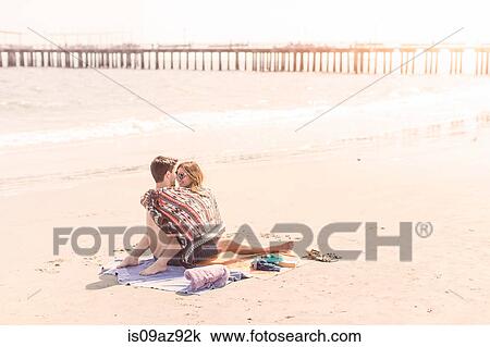 Stock Image - Couple on beach wrapped in blanket, Coney island, Brooklyn, New York, USA. Fotosearch