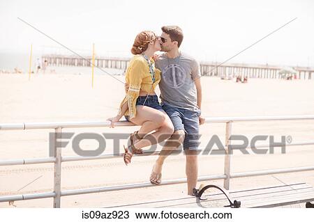 Stock Image - Couple on railings by beach kissing, Coney island, Brooklyn, New York, USA. Fotosearch