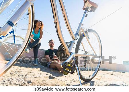 Stock Photo - Couple relaxing after bike ride, bicycles beside them. Fotosearch