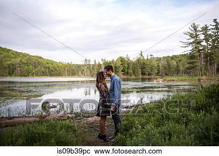 Stock Image - Couple rubbing noses by lake, Ottawa, Ontario. Fotosearch