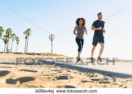 Couple running on pathway at beach, low angle view View Large Photo Image Stock Image - Couple running on pathway at beach, low angle view. Fotosearch
