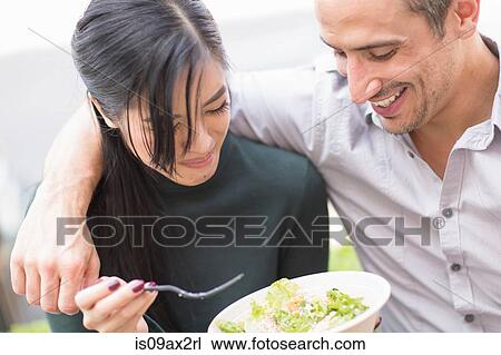 Couple sharing lunch looking down smiling View Large Photo Image Stock Image - Couple sharing lunch looking down smiling. Fotosearch