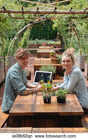 Couple sitting at picnic table looking at camera smiling View Large Photo Image Picture - Couple sitting at picnic table looking at camera smiling. Fotosearch