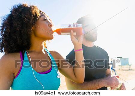 Stock Image - Couple sitting outdoors, drinking fruit juice. Fotosearch