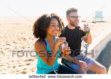 Stock Image - Couple sitting outdoors, drinking fruit juice. Fotosearch