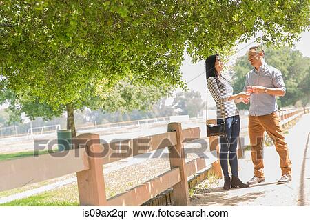 Couple standing underneath tree on fenced path View Large Photo Image Stock Photography - Couple standing underneath tree on fenced path. Fotosearch