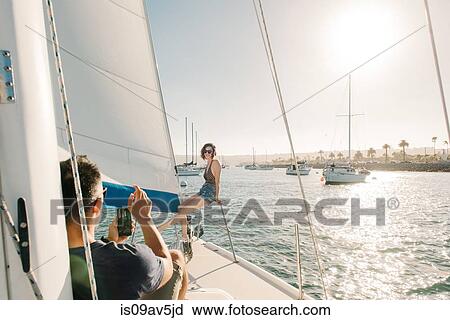 Stock Image - Couple taking photograph on sailboat, San Diego Bay, California, USA. Fotosearch