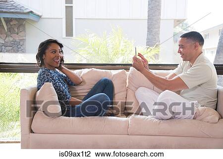 Couple taking photograph on sofa View Large Photo Image Stock Image - Couple taking photograph on sofa. Fotosearch