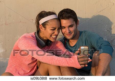Couple taking selfie in front of concrete wall View Large Photo Image Stock Photo - Couple taking selfie in front of concrete wall. Fotosearch