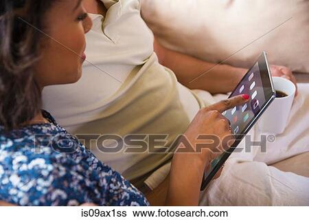 Couple using digital tablet on sofa View Large Photo Image Stock Photograph - Couple using digital tablet on sofa. Fotosearch