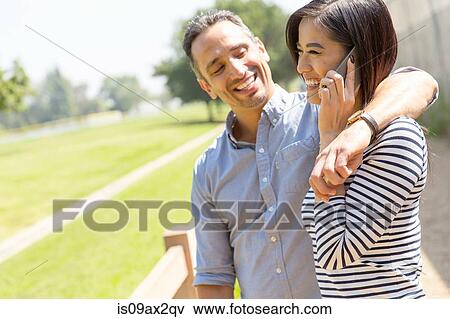 Couple using smartphone to make telephone call smiling View Large Photo Image Stock Photo - Couple using smartphone to make telephone call smiling. Fotosearch