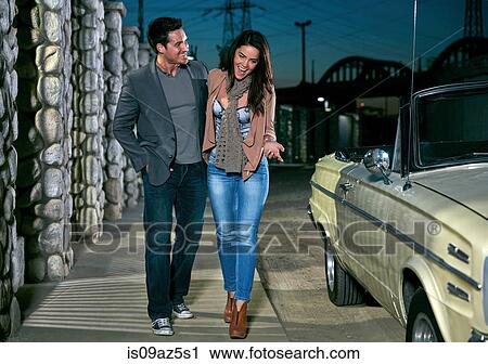 Couple walking in street by convertible classic car at night, Los Angeles, California, USA View Large Photo Image Stock Image - Couple walking in street by convertible classic car at night, Los Angeles, California, USA. Fotosearch