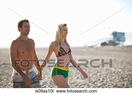 Couple walking on beach holding hands smiling View Large Photo Image Stock Photograph - Couple walking on beach holding hands smiling. Fotosearch