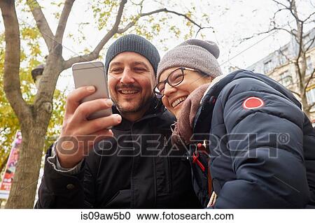 Couple wearing knit hats in park reading smartphone texts View Large Photo Image Stock Image - Couple wearing knit hats in park reading smartphone texts. Fotosearch