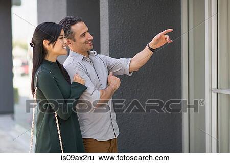 Couple window shopping pointing and smiling View Large Photo Image Stock Photograph - Couple window shopping pointing and smiling. Fotosearch