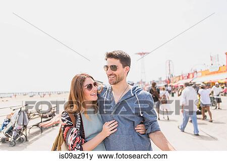Couple with arms around each other walking, Coney island, Brooklyn, New York, USA View Large Photo Image Stock Photo - Couple with arms around each other walking, Coney island, Brooklyn, New York, USA. Fotosearch