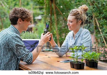 Stock Image - Couple with beer in garden making a toast. Fotosearch