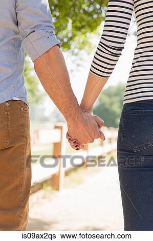 Cropped rear view of couple holding hands View Large Photo Image Stock Photograph - Cropped rear view of couple holding hands. Fotosearch