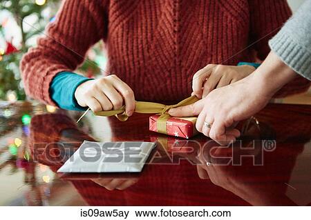 Cropped shot of couples hands wrapping xmas gift at table View Large Photo Image Stock Photo - Cropped shot of couples hands wrapping xmas gift at table. Fotosearch