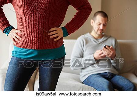 Cropped shot of woman in front of boyfriend on sofa reading smartphone View Large Photo Image Stock Image - Cropped shot of woman in front of boyfriend on sofa reading smartphone. Fotosearch
