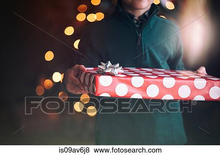 Cropped view of boy in front of christmas tree holding gift View Large Photo Image Stock Photo - Cropped view of boy in front of christmas tree holding gift. Fotosearch