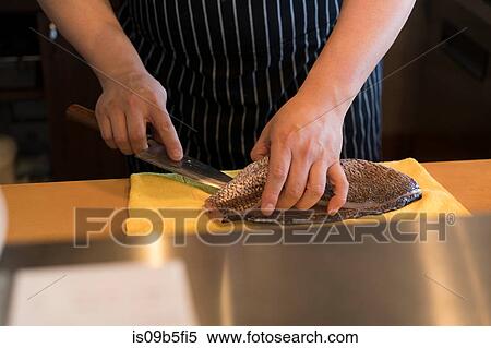 Stock Photography - Cropped view of chef in kitchen preparing fish. Fotosearch