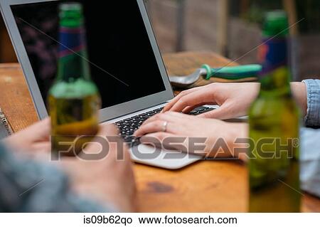 Cropped view of couple drinking beer using laptop View Large Photo Image Picture - Cropped view of couple drinking beer using laptop. Fotosearch