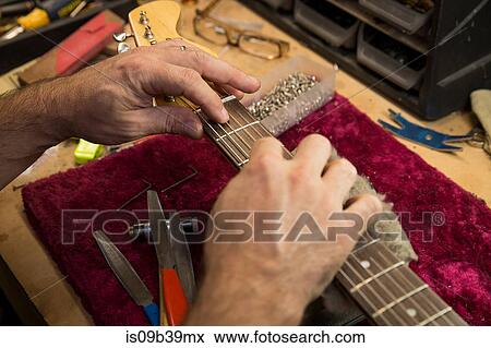 Stock Photo - Cropped view of guitar maker's hands manufacturing guitar. Fotosearch