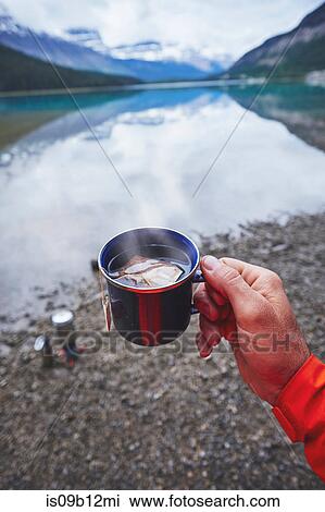 Cropped view of mans hand holding cup of tea by river, Banff, Alberta, Canada View Large Photo Image Stock Image - Cropped view of mans hand holding cup of tea by river, Banff, Alberta, Canada. Fotosearch